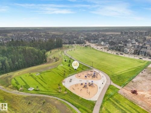 Expansive community park featuring multiple playground structures on a sand surface, surrounded by manicured green spaces - 5281 Edgemont Boulevard Nw, Edmonton, AB - Outdoor With View