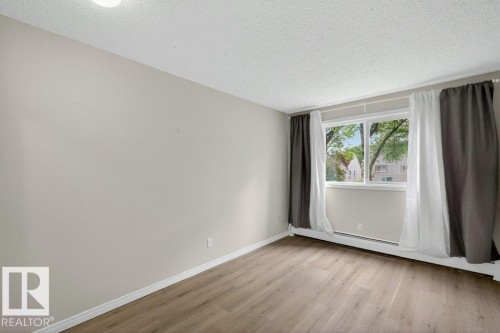 Interior room featuring light wood-finish flooring and a large window - 103 10620 104 Street Nw, Edmonton, AB 