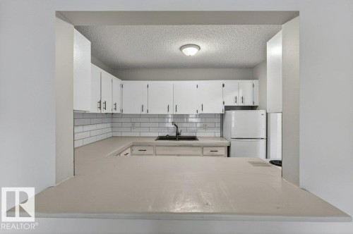 Kitchen with white cabinetry, subway tile backsplash, and a breakfast bar - 103 10620 104 Street Nw, Edmonton, AB 