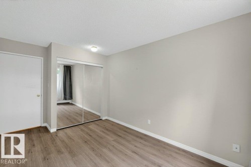 Spacious room featuring wood-finish flooring, light gray walls, white trim, and a ceiling light fixture - 103 10620 104 Street Nw, Edmonton, AB 