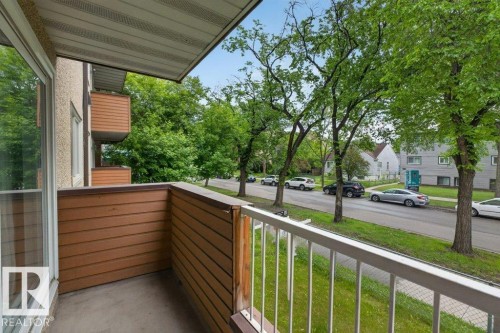 Private balcony with concrete flooring, horizontal wood-look paneling, and white metal railings - 103 10620 104 Street Nw, Edmonton, AB 