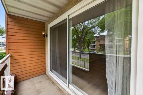 Balcony with wood-paneled wall, white railing, and exterior wall light fixture - 103 10620 104 Street Nw, Edmonton, AB 