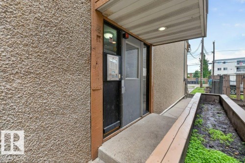 Entryway featuring a textured stucco exterior, an intercom system, and a concrete pathway - 103 10620 104 Street Nw, Edmonton, AB 
