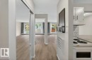 Open-concept living space with wood-finish flooring, light-toned walls, and multiple large windows - 103 10620 104 Street Nw, Edmonton, AB 