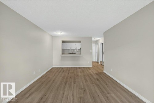 Open concept living area featuring wood-finish flooring, light gray wall paint, and white baseboards - 103 10620 104 Street Nw, Edmonton, AB 
