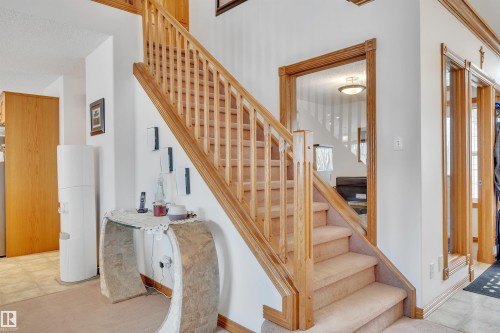 Staircase featuring wood railings and newel posts with carpeted treads - 16512 87 Street, Edmonton, AB 