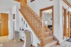 Staircase featuring wood railings and newel posts with carpeted treads - 