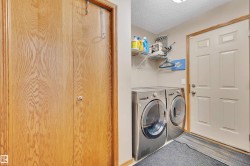 Dedicated laundry area featuring front-loading machines, wall-mounted shelving, and a paneled entry door - 