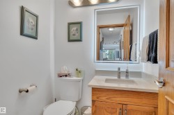 Bathroom featuring a wood vanity with a light-colored countertop, an integrated sink, and an illuminated mirror - 