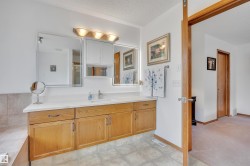 Double vanity with a single basin, light wood-finish cabinetry, and a light-colored countertop - 