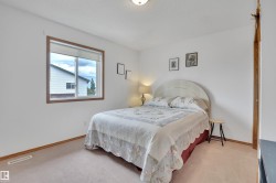 Carpeted bedroom with a single window featuring a wood-finish frame and roller shade - 