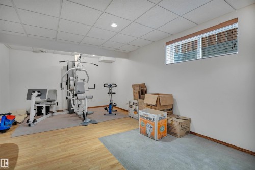 Lower-level bonus room with light wood-finish flooring, recessed lighting, and a drop ceiling - 16512 87 Street, Edmonton, AB 