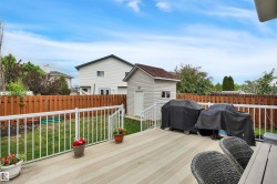 Spacious composite deck with white railings overlooks a fenced backyard featuring a detached storage shed - 