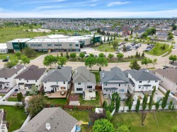 Aerial view showcasing the property's proximity to a contemporary school building with a large parking area - 
