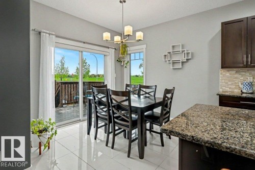 Dining area featuring white large-format floor tiles and a contemporary chandelier - 13004 164 Avenue, Edmonton, AB 