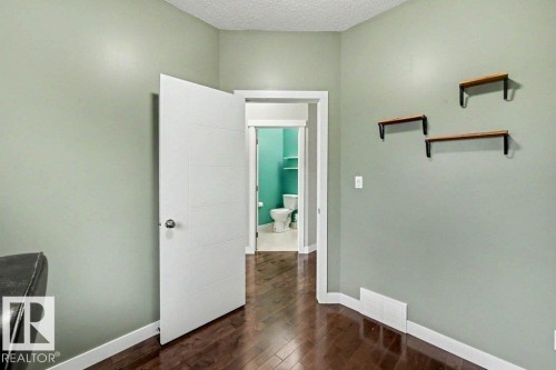 Hardwood-finish flooring extending from the foreground into an interior room with a paneled door - 13004 164 Avenue, Edmonton, AB 