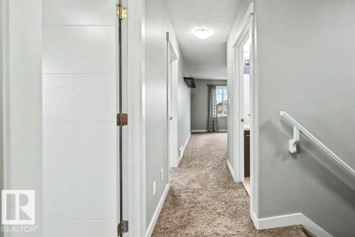 Hallway featuring light gray walls, white trim, and textured carpeting - 13004 164 Avenue, Edmonton, AB 