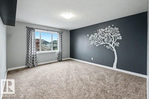 Spacious interior room featuring plush carpet flooring and a prominent accent wall with a decorative tree decal - 13004 164 Avenue, Edmonton, AB 