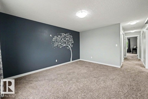 Spacious room featuring a dark accent wall with a tree motif and light grey walls - 13004 164 Avenue, Edmonton, AB 