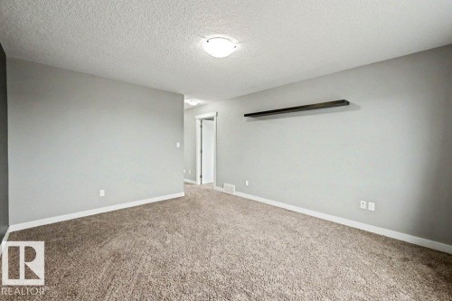 Spacious room featuring neutral carpeting, light gray wall paint, and white trim - 13004 164 Avenue, Edmonton, AB 