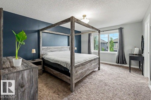 Bedroom featuring a window with exterior views, dark accent wall, textured carpet flooring, and a ceiling-mounted light fixture - 13004 164 Avenue, Edmonton, AB 