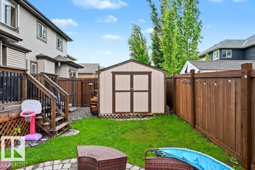 Backyard featuring a detached storage shed, wood privacy fencing, and a multi-level deck with wood railing - 13004 164 Avenue, Edmonton, AB 