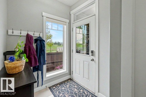 Entryway featuring a white paneled door with glass inserts, a transom window, and an adjacent full-height window with grid detailing - 13004 164 Avenue, Edmonton, AB 
