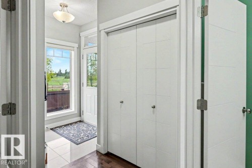 Entryway featuring a white paneled front door with decorative glass, a large window, and recessed bi-fold closet doors - 13004 164 Avenue, Edmonton, AB 