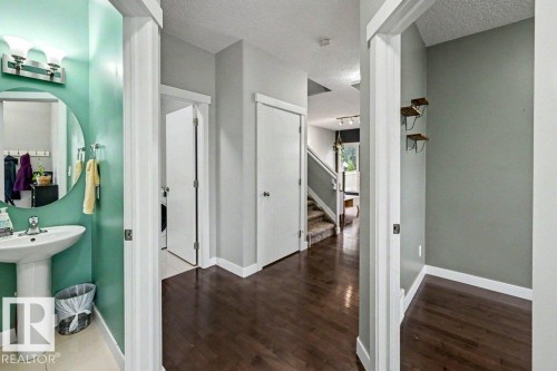 Hallway featuring dark wood-finish flooring, light grey walls, and white trim - 13004 164 Avenue, Edmonton, AB 