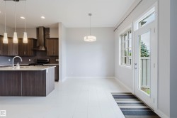 Open-concept living space featuring a kitchen island with pendant lighting, stone countertops, and dark wood-finish cabinetry - 