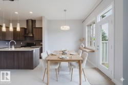 Bright dining area featuring a light wood-finish table, white tile flooring, and a contemporary pendant light fixture - 