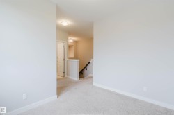 Carpeted room with light-toned walls, white baseboards, and a doorway featuring a paneled door - 