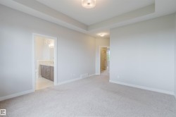 Neutral-toned carpeting extends throughout this interior space, featuring a tray ceiling with a flush-mount light fixture - 