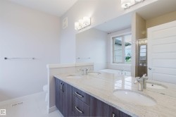 Dual vanity featuring a light-toned countertop, under-mount sinks, and chrome faucets - 
