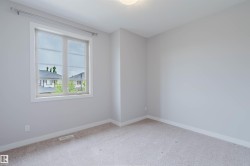 Bright interior room featuring a large window with white trim, neutral wall tones, light-colored carpeting, and a flush-mount ceiling light fixture - 
