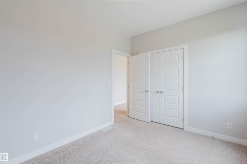 Neutral tone walls with white trim, light-colored carpet, and paneled double doors - 2921 Anderson Crest, Edmonton, AB 