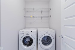 Dedicated laundry area featuring front-loading appliances, white walls, and built-in wire shelving - 