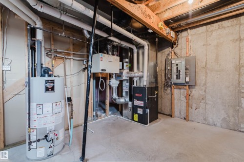 Utility room featuring a water heater, furnace, electrical panel, and exposed concrete walls - 2921 Anderson Crest, Edmonton, AB 