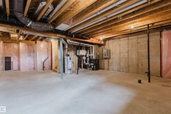 Unfinished lower level featuring exposed ceiling joists, concrete flooring, and insulated wall framing - 