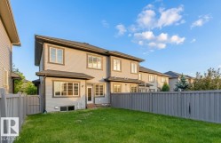 Rear exterior featuring light-colored siding, dark trim, and multiple large windows - 