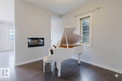 Open-concept interior featuring wood-finish flooring, a built-in linear fireplace, and modern windows with white trim - 