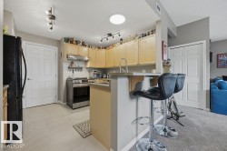 Kitchen featuring light wood cabinetry, stainless steel range, and a breakfast bar with countertop seating - 