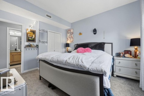 Carpeted bedroom featuring a double-door closet, access to a bathroom, and light blue walls - 71 3040 Spence Wynd, Edmonton, AB 
