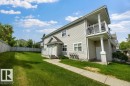 Modern multi-story structure with light-colored siding, featuring a second-story balcony with white railing, a ground-level patio, and a front entry with a small porch - 71 3040 Spence Wynd, Edmonton, AB 