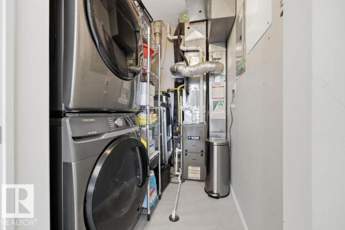 Dedicated utility space featuring stacked front-load laundry appliances, a YORK HVAC system, and light gray painted walls - 71 3040 Spence Wynd, Edmonton, AB 