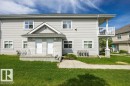 Two-story residential building featuring light-toned siding, white trim windows, and a prominent front porch with white railings - 71 3040 Spence Wynd, Edmonton, AB 