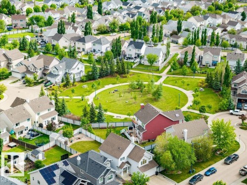 Aerial perspective showcasing a residential community with diverse home exteriors, a central green space, and mature trees - 71 3040 Spence Wynd, Edmonton, AB 