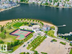 Lakeside community with multiple tennis courts, recreational green space, sandy beach area, and private boat docks - 