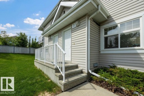 Exterior siding with white trim, concrete steps, and a white railing leading to a white entry door - 71 3040 Spence Wynd, Edmonton, AB 
