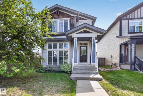 Two-story residence featuring a covered front porch, concrete pathway, and mature landscaping - 9847 220 Street, Edmonton, AB 